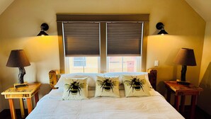 Un dormitorio con una cama grande, dos lámparas de noche y una ventana con persianas.