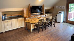 Una cocina con una mesa y sillas de madera, un televisor y un refrigerador.