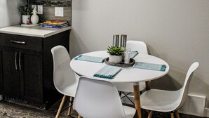 A compact kitchen with a microwave, cabinets, and a round wall clock. - Home away from home (Grande Prairie)