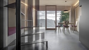 Een modern interieur met een trap, een eethoek met stoelen en een tafel, en een groot raam met uitzicht op de bergen.