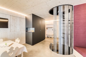 A modern interior with a wooden ceiling, a fireplace, a seating area, and a unique perforated column.