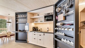 Een moderne keuken met houten kastjes, een inbouwoven en een koffieapparaat.