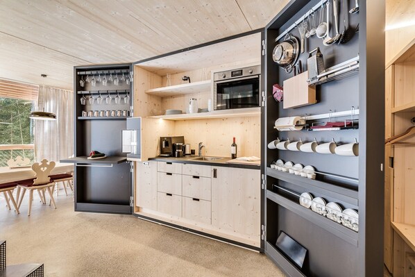 Une cuisine moderne avec des meubles en bois, un four encastré et une machine à café.
