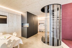 Ein modernes Interieur mit Holzbalkendecke, Kamin, Sitzecke und einer markanten, perforierten Säule.