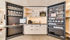 Una cocina compacta con microondas, cafetera y varios utensilios en estantes.