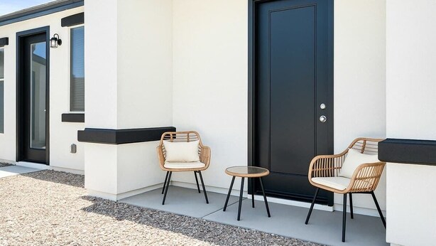A modern building with a black door, two wicker chairs, and a small round table on a gravel path. - 3BD / Free Parking / 75" Smart TV / 2BR / 2Bath (Glendale)
