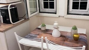 A small kitchen with a microwave, coffee maker, and a table with chairs. There are potted plants on the table. - Guest house that's love rome (Roma)