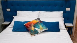 A bed with a blue headboard, white bedding, and a colorful pillow. - Guest house that's love rome (Roma)