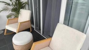 Ein Balkon mit zwei Korbstühlen und einem kleinen, runden Hocker.