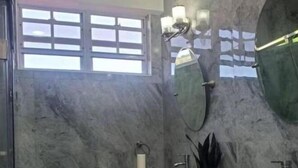 Ein Badezimmer mit einem großen Spiegel, zwei Waschbecken, einem Fenster und einer Marmorwand.