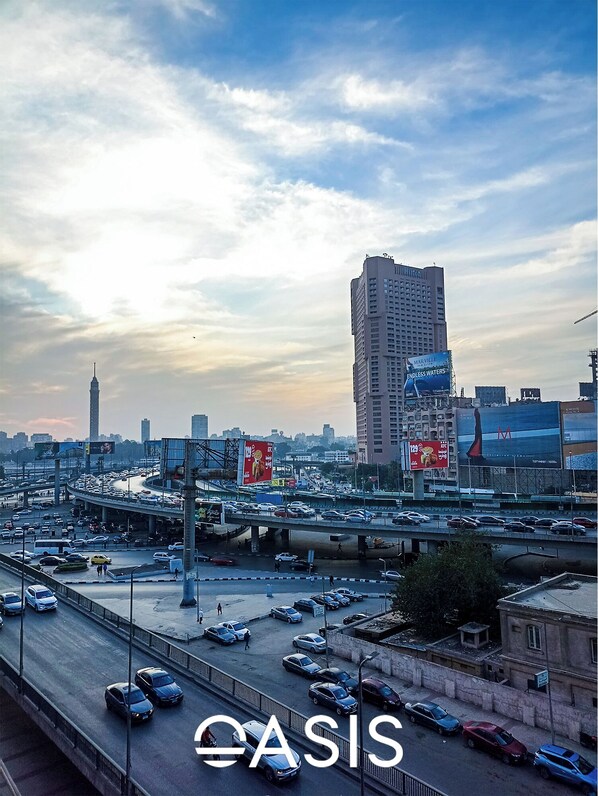 A busy urban highway with multiple lanes of traffic, overpasses, and high-rise buildings in the background. - OASIS Hotel Downtown (Cairo)