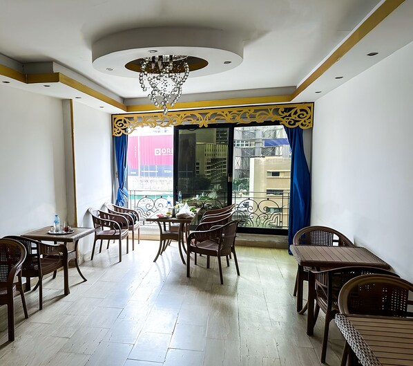 A dining area with wooden furniture and a view of the city through large windows. - OASIS Hotel Downtown (Cairo)