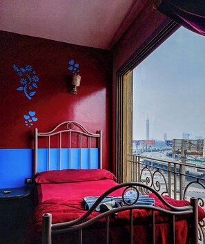 A room with a bed, a window with a view of a cityscape, and a wall with a floral design. - OASIS Hotel Downtown (Cairo)