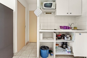 Une petite cuisine équipée d’un four à micro-ondes, d’un évier et d’étagères de rangement.
