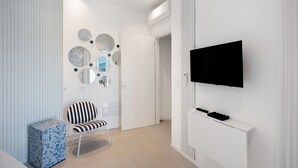 A modern room with a TV mounted on the wall, a striped chair, and a decorative wall with circular mirrors.