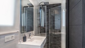 Une salle de bain moderne avec une douche à parois de verre, un lavabo blanc et un grand miroir.