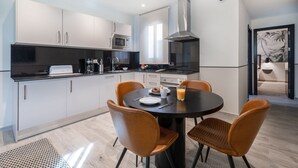 Une cuisine moderne avec des meubles blancs, un plan de travail noir et une table de salle à manger ronde, accompagnée de quatre chaises.