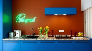 Eine Küche mit einer Neonreklame, einem blauen Schrank und einer Arbeitsplatte mit Obstschale.