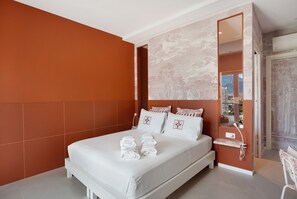 A modern hotel room with a large bed, a nightstand, and a mirror. - Room 'Camera Deluxe Fuoco' with Mountain View, Wi-Fi and Air Conditioning (Pompei)