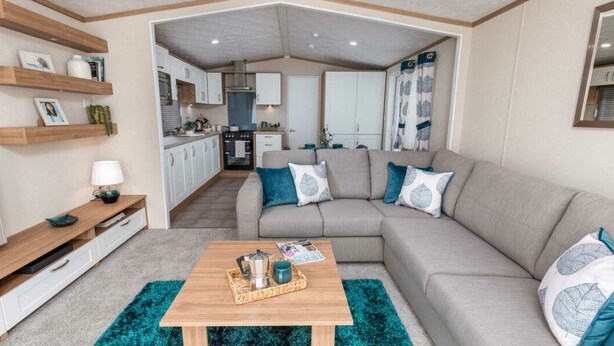 A modern living room with a sofa, coffee table, and wooden shelves. - Waterside Haven (Northampton)