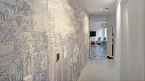 A hallway with a textured wall, a door, and a glimpse of a room with a radiator and a television. - Room 'Superior Terra' with Mountain View, Wi-Fi and Air Conditioning (Pompei)