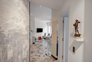 A hallway with a patterned wall, a statue, and a television mounted on the wall.
