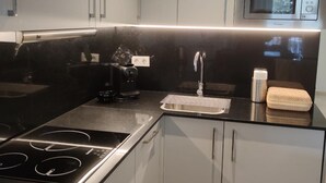A modern kitchen with a black countertop, stainless steel appliances, and white cabinets. - Superior 1 Bedroom Apartment (Sevilla)