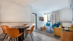 A modern living room with a dining area, featuring a round table with chairs, a sofa, and a coffee table.
