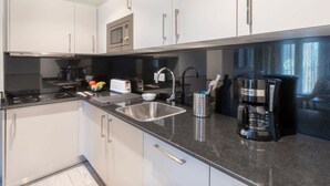 A modern kitchen with white cabinets, a stainless steel sink, a coffee maker, and a toaster.
