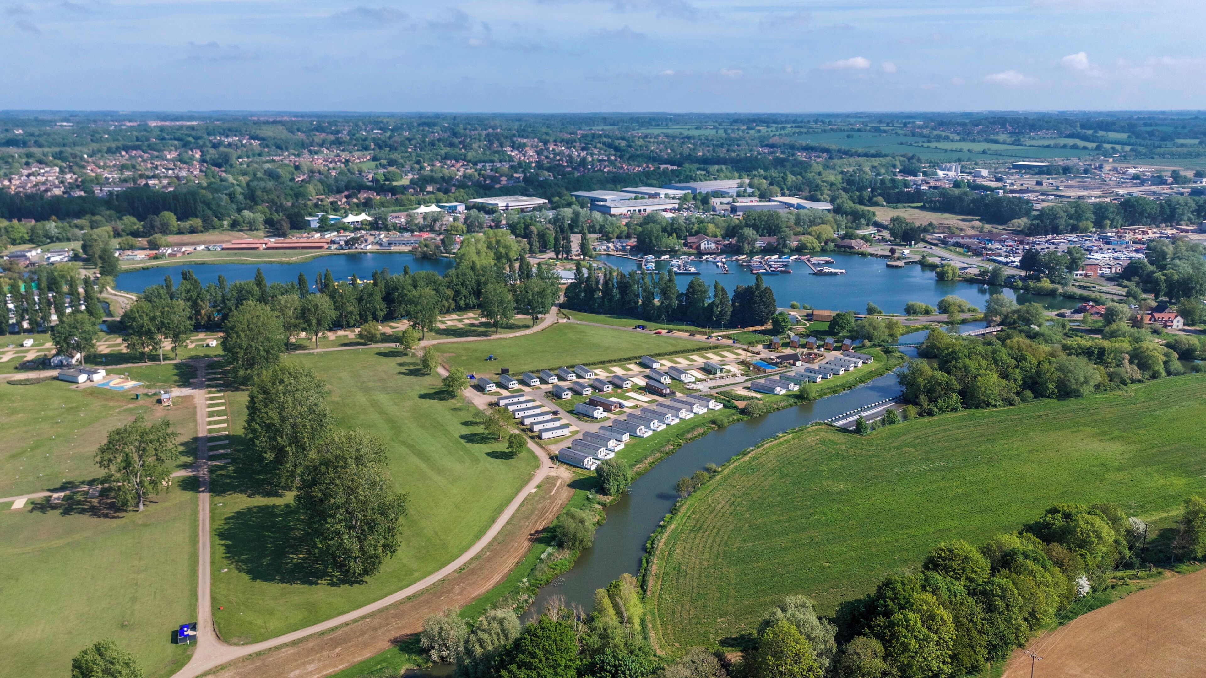 An aerial view of a lakeside campground with RVs, a golf course, and a marina.