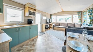 Een compact interieur van een camper met een kitchenette, een zithoek en een eethoek.