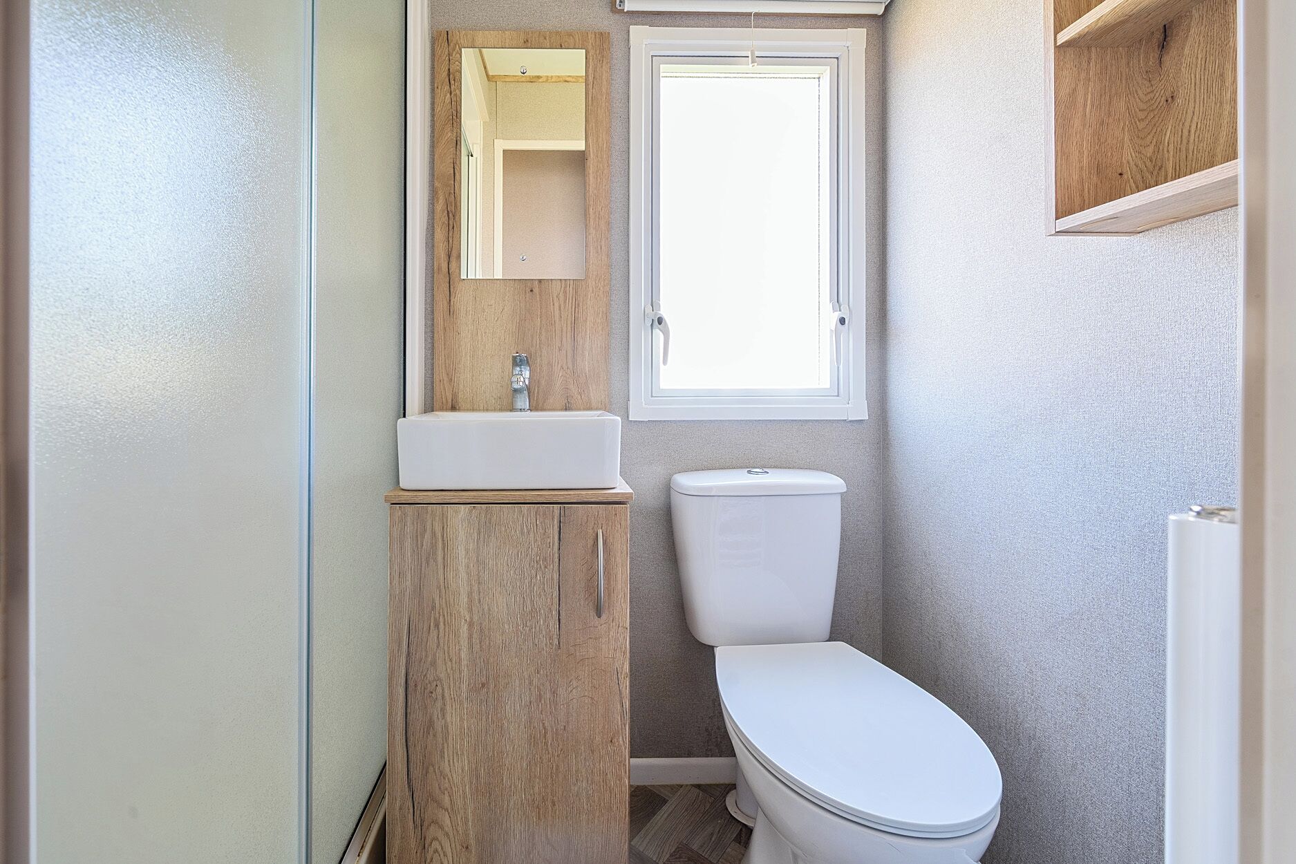 Une petite salle de bain avec un meuble-lavabo en bois, un lavabo blanc et des toilettes.