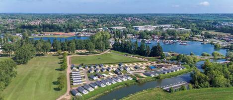 Vista aérea de un camping junto al lago con varias áreas para vehículos recreativos, un puerto deportivo y zonas residenciales circundantes.