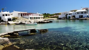 A coastal building with a clear view of the water, a dock, and rocky terrain. - Villa 'Mottarone Cerca De Mar' with Private Pool, Wi-Fi and Air Conditioning (Sant Lluís)