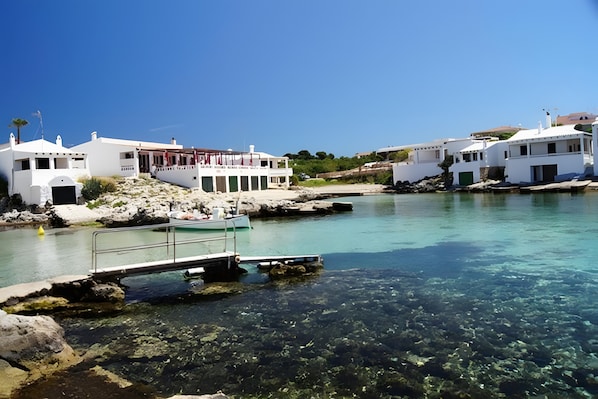 A coastal building with a clear view of the water, a dock, and rocky terrain.