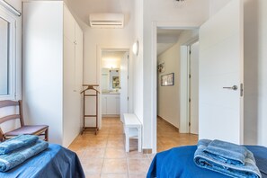 Una habitación de hotel con una cama, una silla, un banco y una puerta que da a un baño.