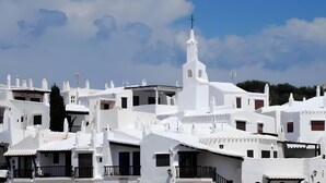 A white-washed village with a prominent church featuring a cross on its tower. - Villa 'Mottarone Cerca De Mar' with Private Pool, Wi-Fi and Air Conditioning (Sant Lluís)