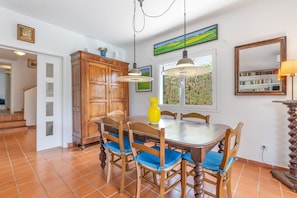 A dining area with a wooden table, chairs, and a yellow vase.