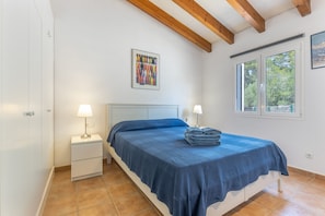 A bedroom with a bed, two bedside tables, a window, and a door.