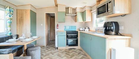 A compact kitchen with a microwave, toaster, and stove. There is a dining area with a table and chairs.