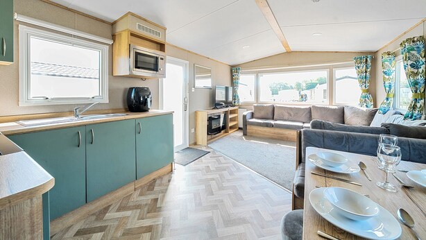 A compact RV interior with a kitchenette, a seating area, and a dining space. - Brookside Bliss - Billing Aquadrome (Northampton)