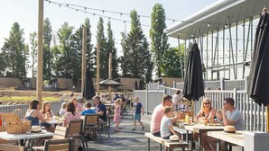 Ein Essbereich im Freien mit Holztischen und -bänken, umgeben von einer Holzterrasse und Lichterketten.
