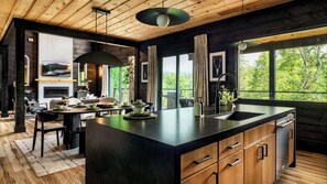 A modern kitchen with a large island, wooden cabinets, and a view of the outdoors.