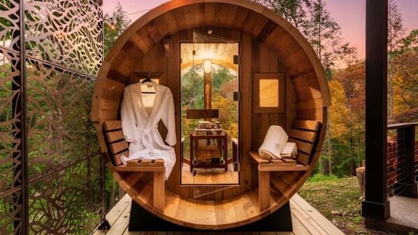 A circular wooden structure with a bench and a chair, a small table, and a window.