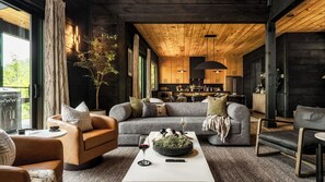 A modern living room with a sofa, coffee table, and a dining area in the background.