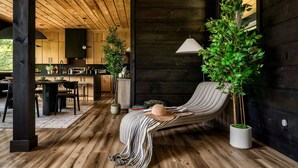 Une pièce chaleureuse avec un plafond en bois, un fauteuil confortable, un coin repas et une cuisine.