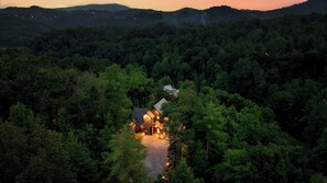 A secluded cabin surrounded by dense forest, accessible by a narrow path.