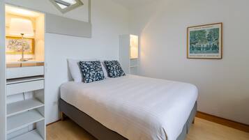 Un dormitorio con cama, estanterías empotradas, tragaluces e imagen enmarcada en la pared.