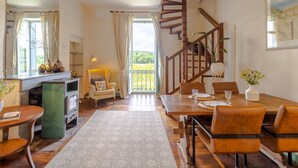Ein Essbereich mit Holztisch, Stühlen, Kamin und Wendeltreppe.