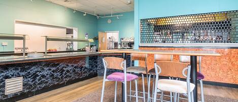 A bar area with a marble counter, stools, and a tiled ceiling.